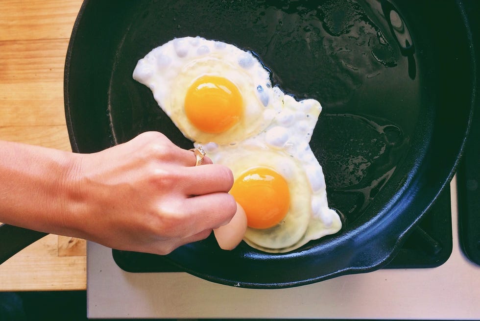 Cropped Hand Of Woman Cooking Omelet In Pan On Stove