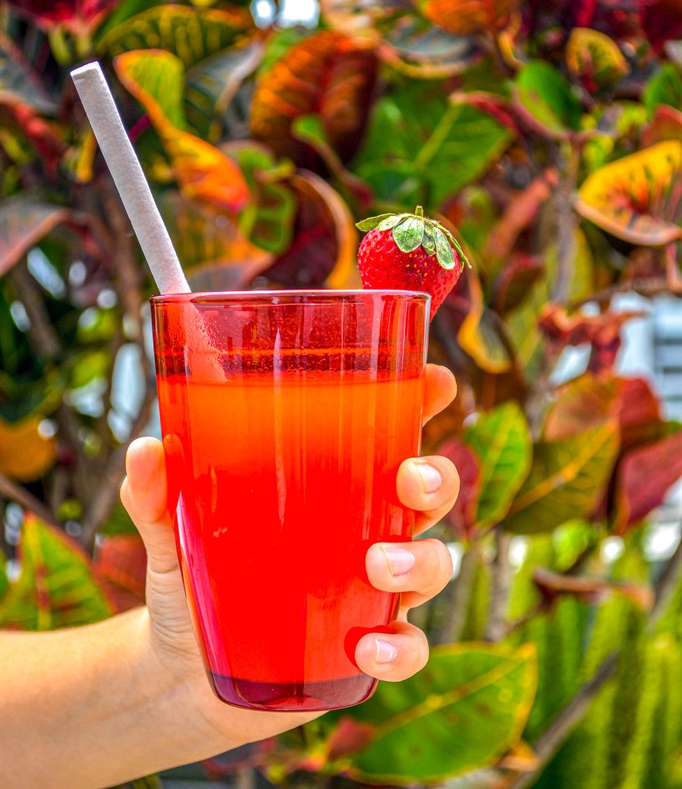 cropped hand of woman holding a fruity drink with a strawberry