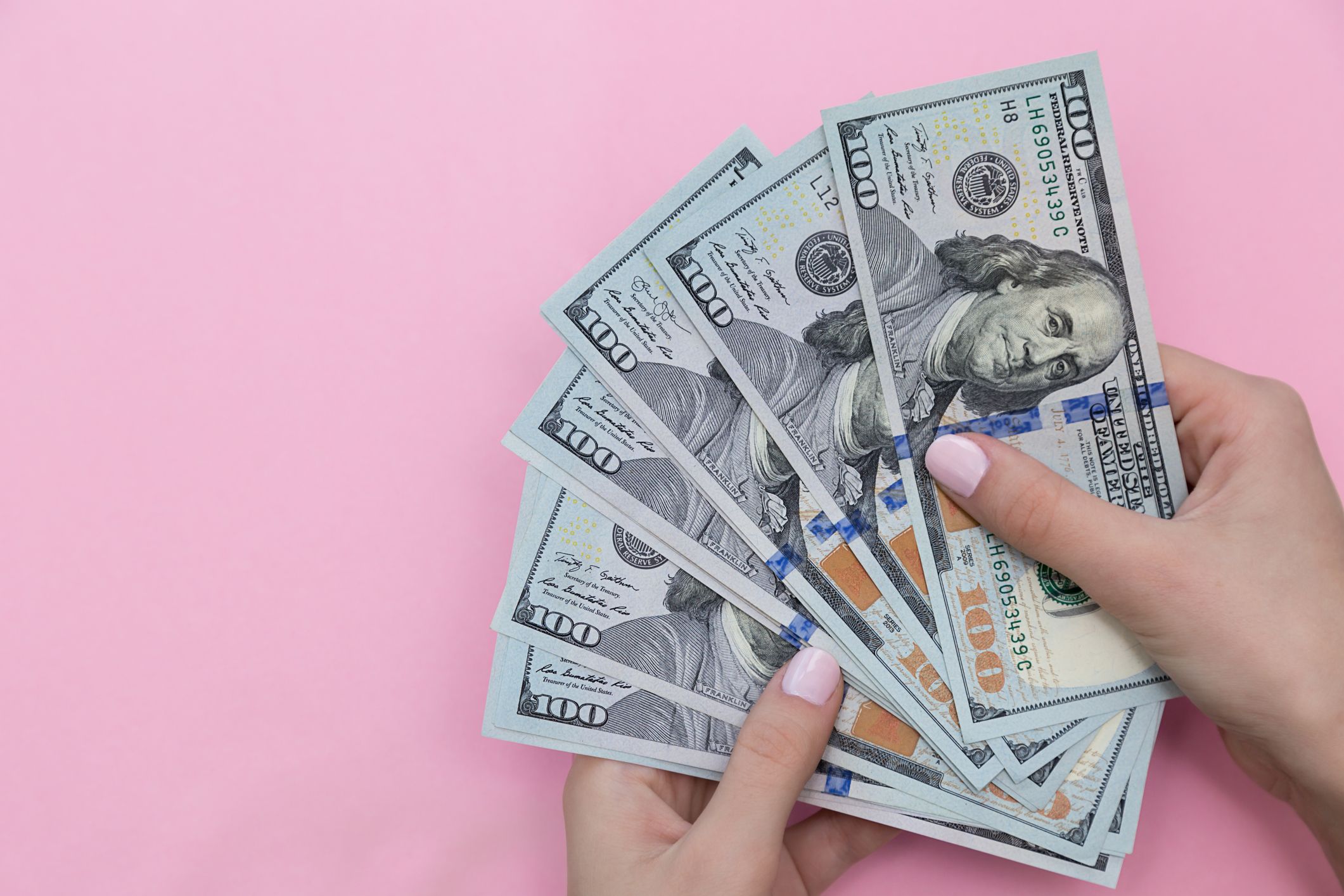 Cropped Hand Of Woman Holding Paper Currencies Against Pink Background