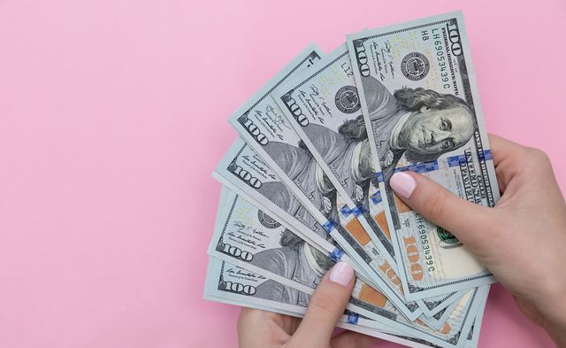 Cropped Hand Of Woman Holding Paper Currencies Against Pink Background