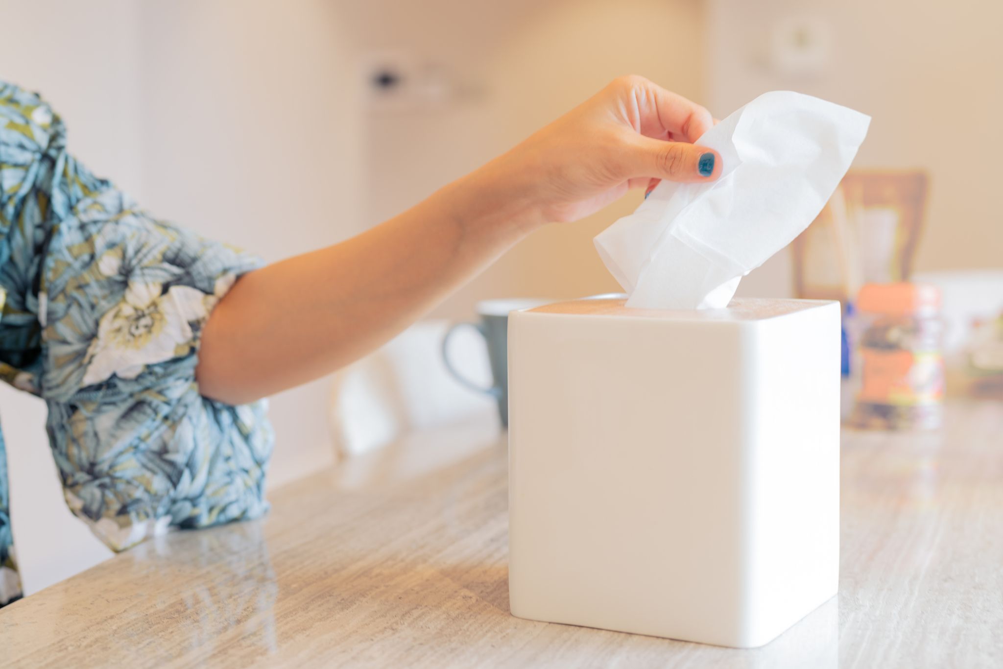 Cropped Hand Of Woman Pulling Tissue From Box On Table