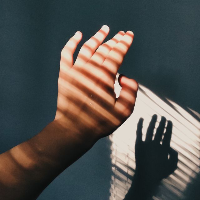 cropped hand of woman with shadow against wall