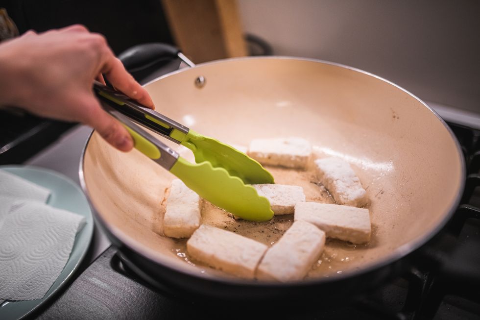 cropped hand preparing fried tofu in kitchen,poland