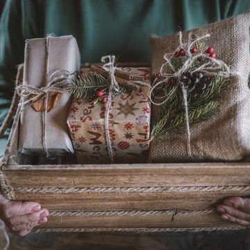 cropped hands arrange christmas presents in wooden crate
