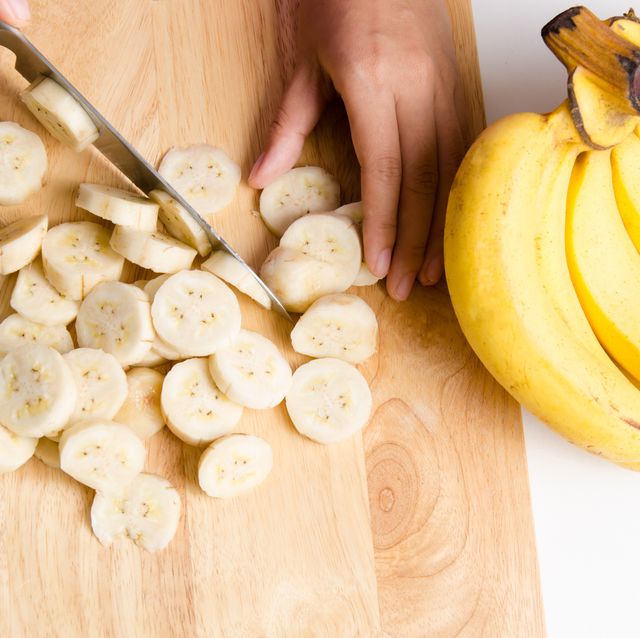 cropped hands cutting banana on chopping board