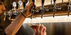 Cropped Hands Of Bartender Filling Beer Glass At Bar