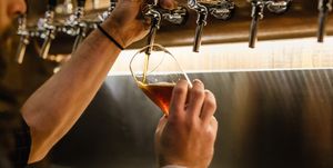 Cropped Hands Of Bartender Filling Beer Glass At Bar