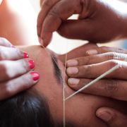 cropped hands of beautician threading woman eyebrows