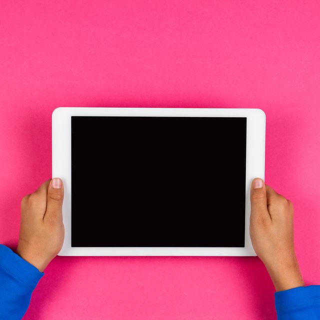 Cropped Hands Of Boy Holding Digital Tablet Over Colored Background