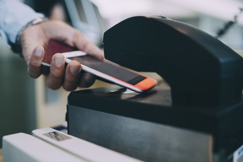 Cropped hands of businessman scanning ticket on smart phone at airport check-in counter
