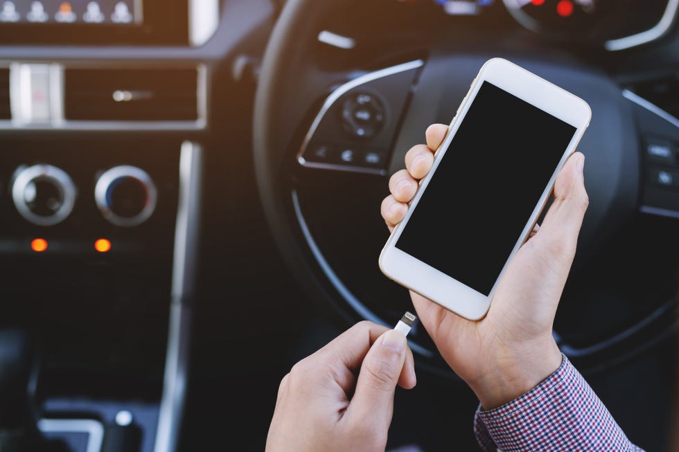 person unplugging iphone from car bluetooth in front of wheel, giving up listening to music in the car for lent