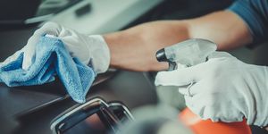 cropped hands of man cleaning dashboard in car
