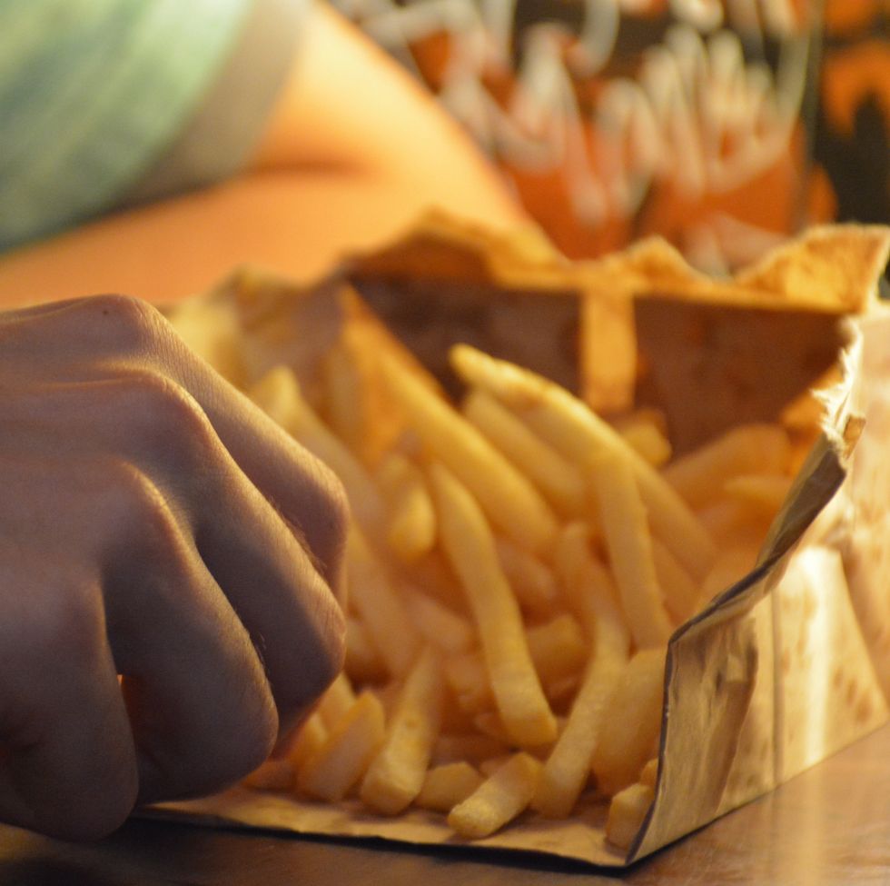 cropped hands of man eating french fries