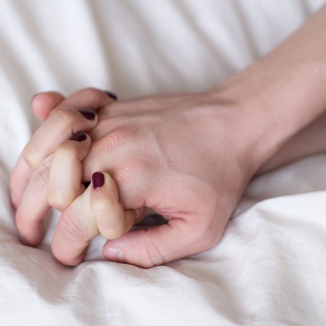 cropped hands of passionate couple on bed at home