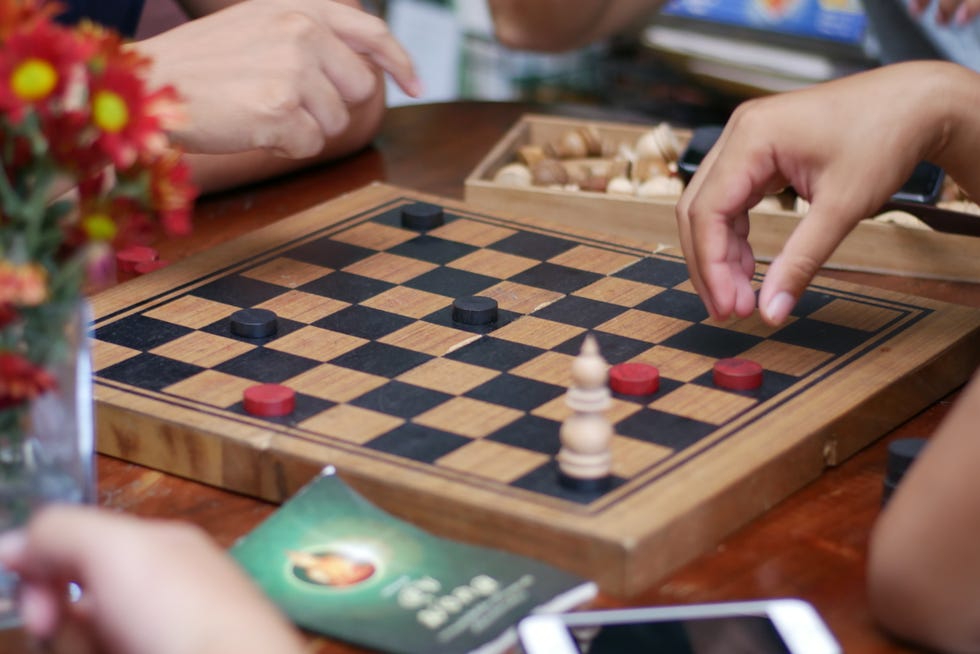 Cropped Hands Of People Playing Board Game On Table