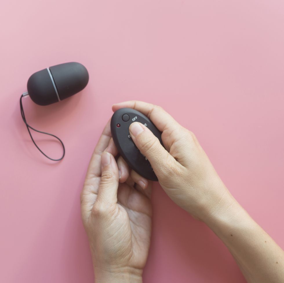 cropped hands of person holding remote control against pink background