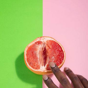 cropped hands of person touching grapefruit over two tone background