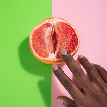 cropped hands of person touching grapefruit over two tone background