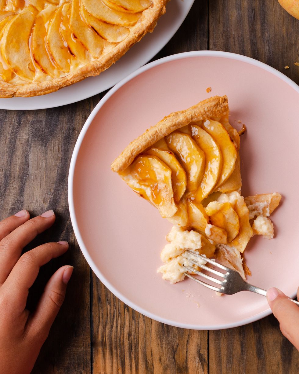 cropped hands of woman having apple pie at table