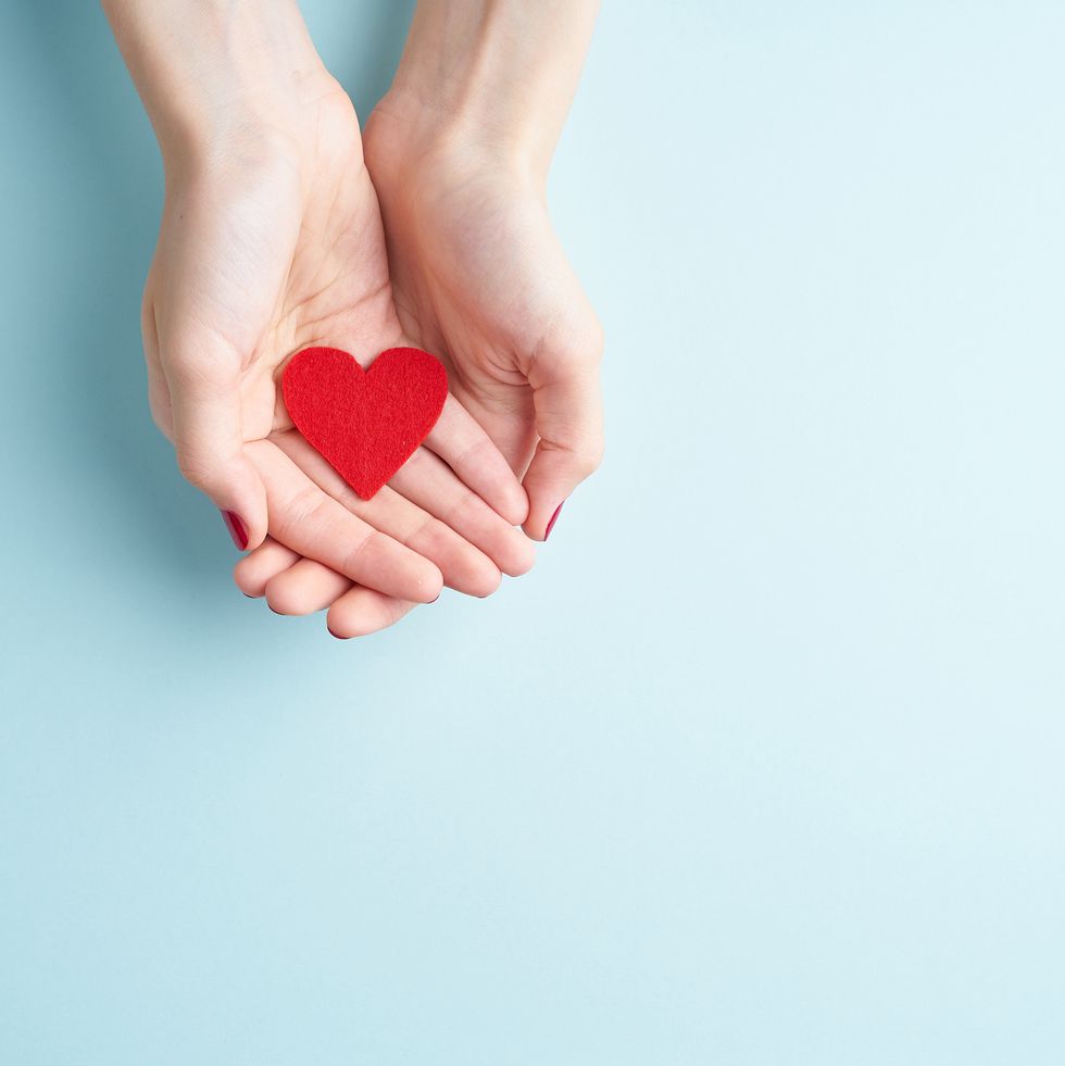 cropped hands of woman holding heart shape over blue background