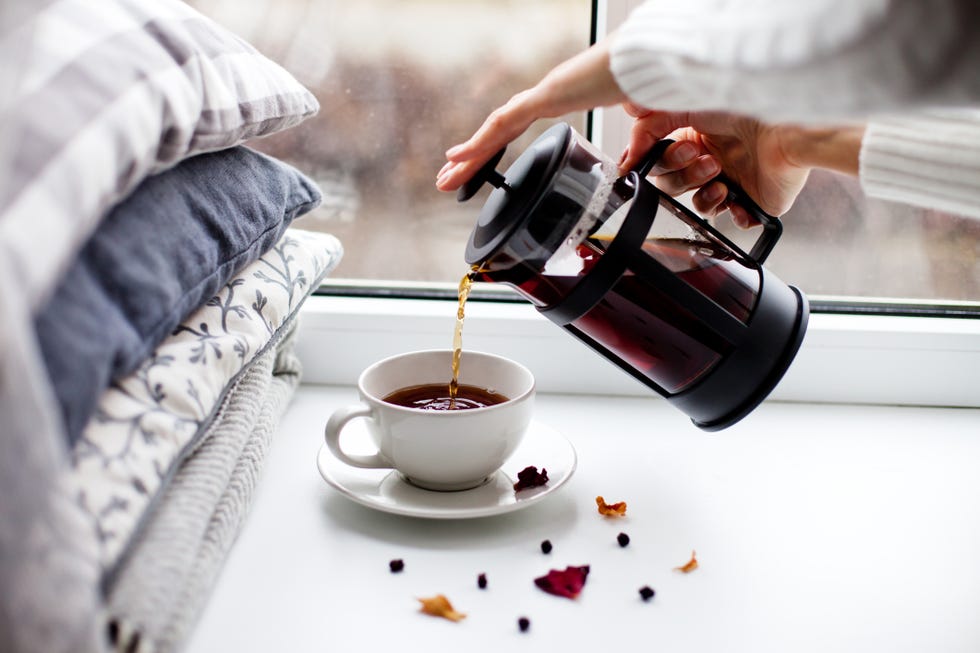 cropped hands of woman pouring coffee in cup on table
