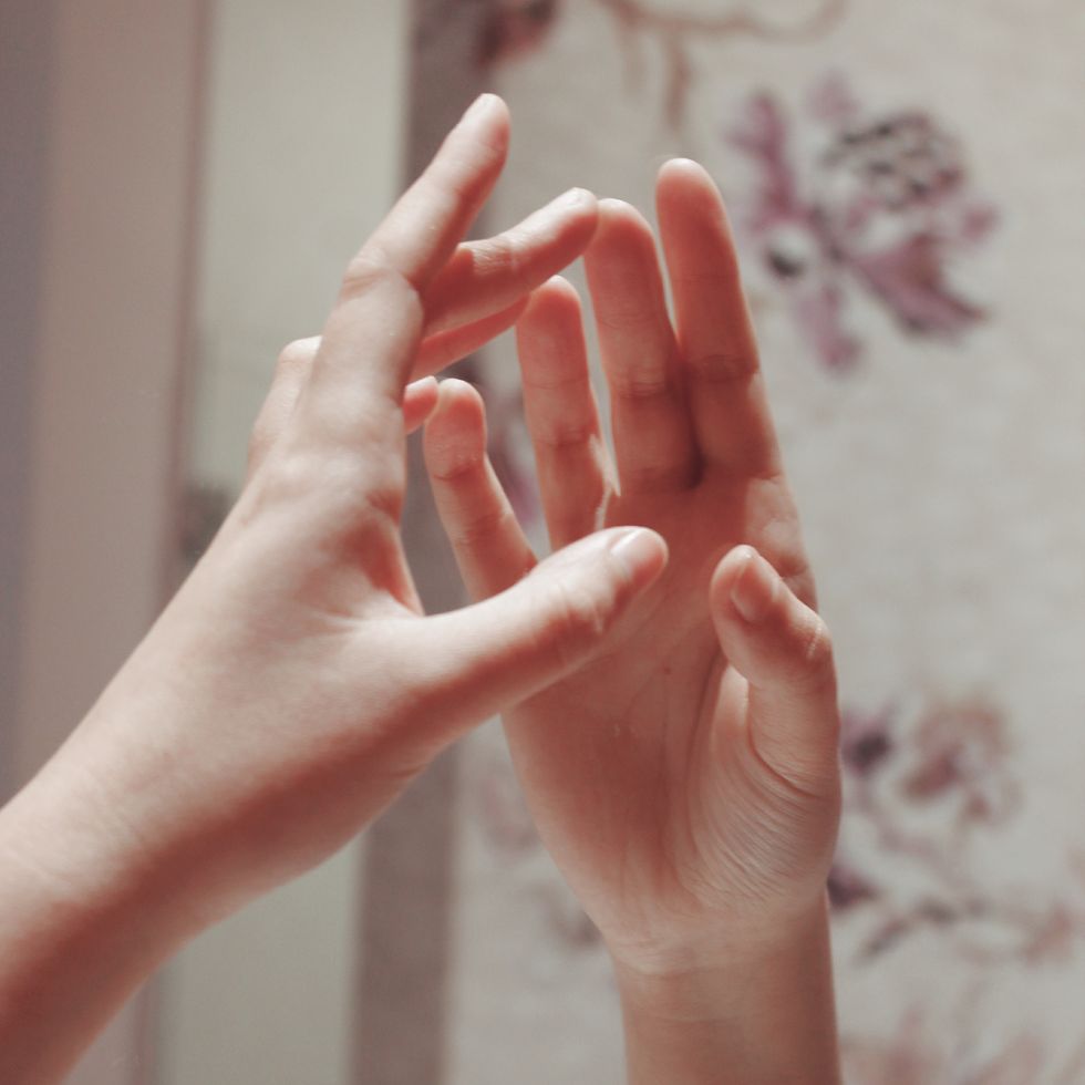 cropped hands of woman touching mirror at home