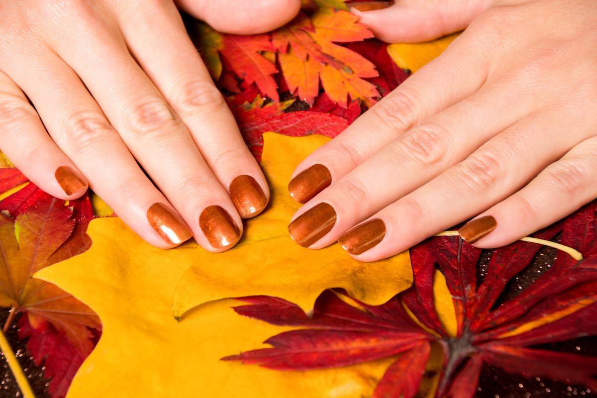 Cropped Hands Of Woman With Nail Polish On Dry Leaves
