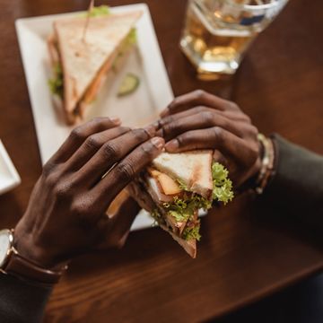 cropped image of african american man holding sandwich