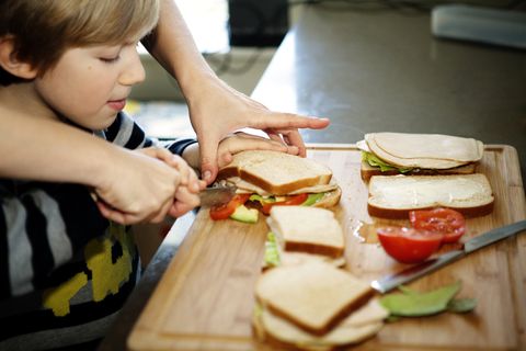cropped image of father making sandwich with son in kitchen
