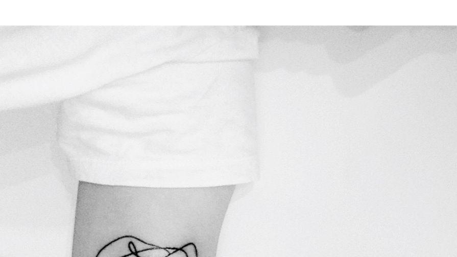 cropped image of hand with tattoo on bed