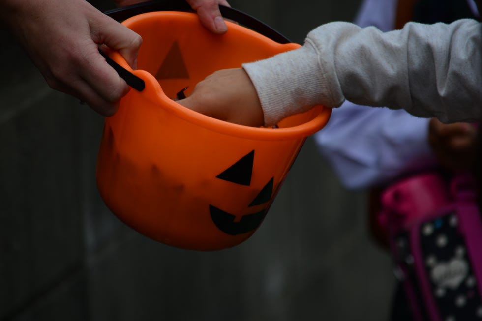 Cropped Image Of Hands Picking Candy From Halloween Basket