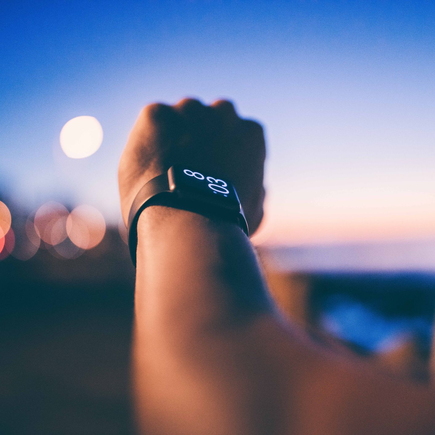 Cropped Image Of Man Hand Wearing Smart Watch Against Sky During Sunset