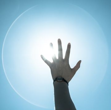 cropped image of person reaching towards bright sun