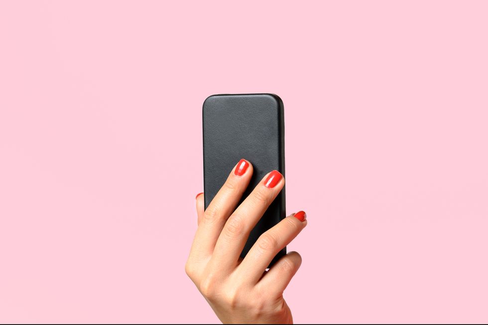 Cropped Image Of Woman Hand Holding Mobile Phone Against Pink Background