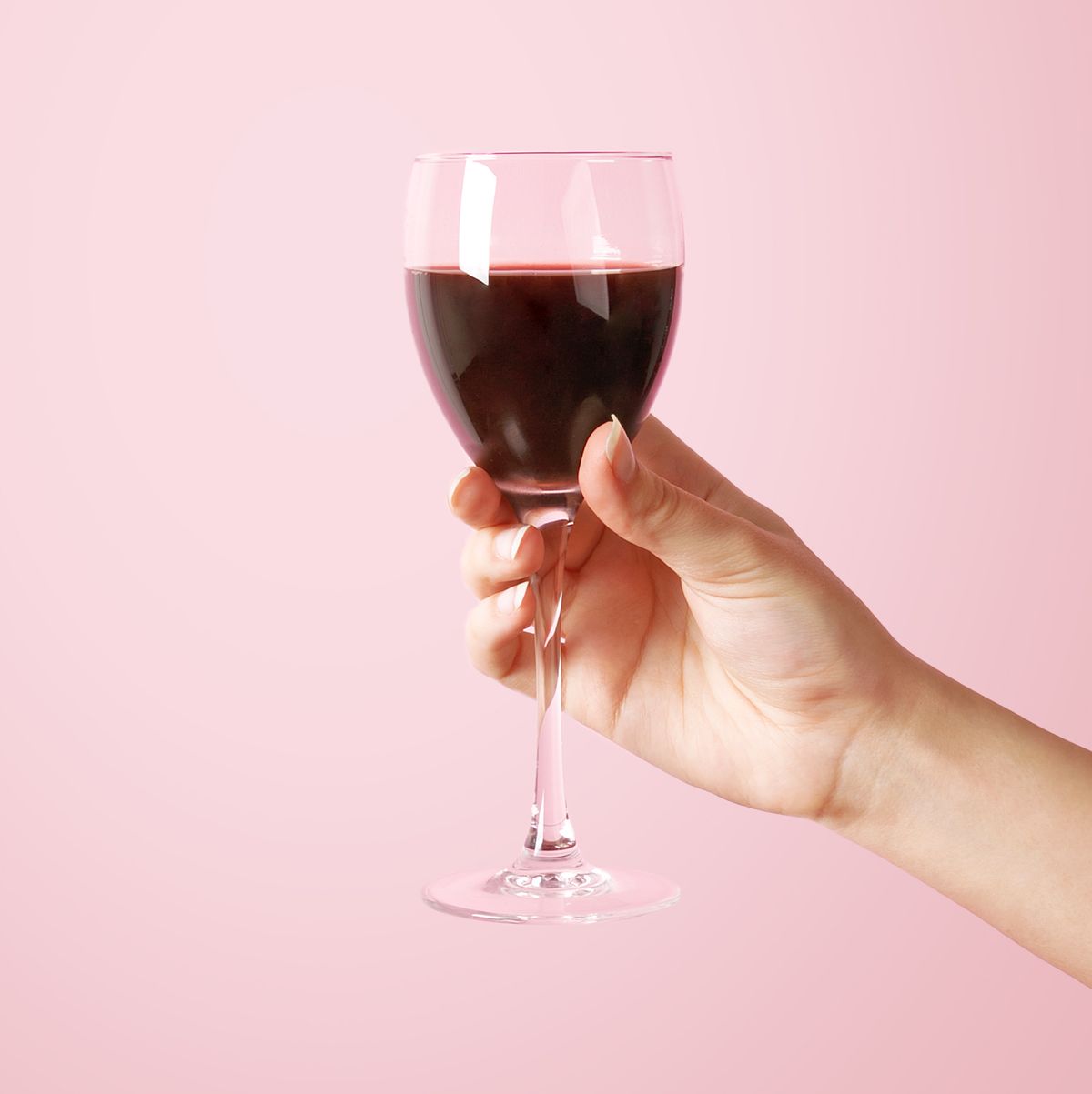 woman holding wine glass on pink background