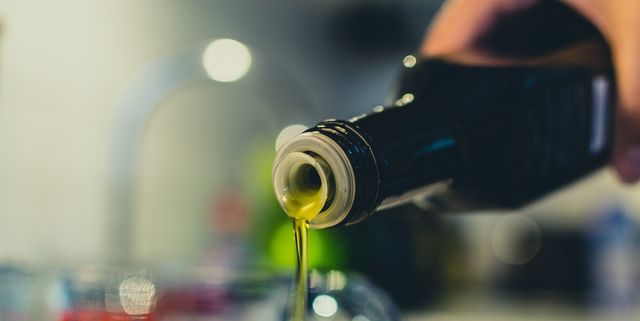 Cropped Image Of Woman Pouring Olive Oil In Jar