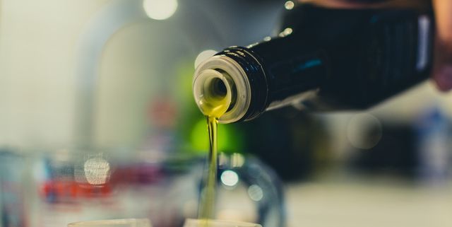 Cropped Image Of Woman Pouring Olive Oil In Jar