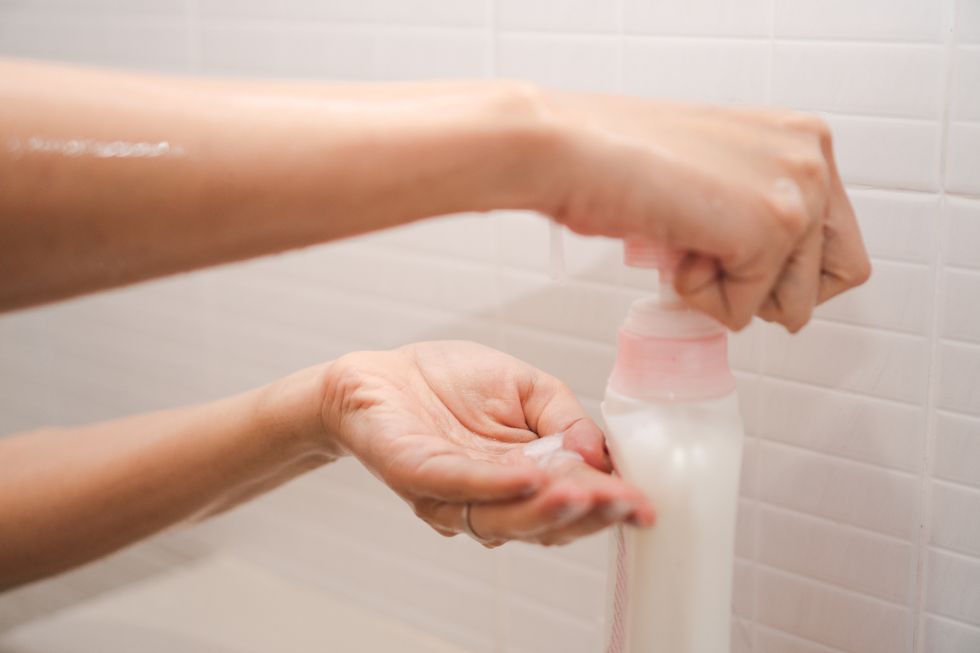 cropped image of woman taking shampoo in bathroom
