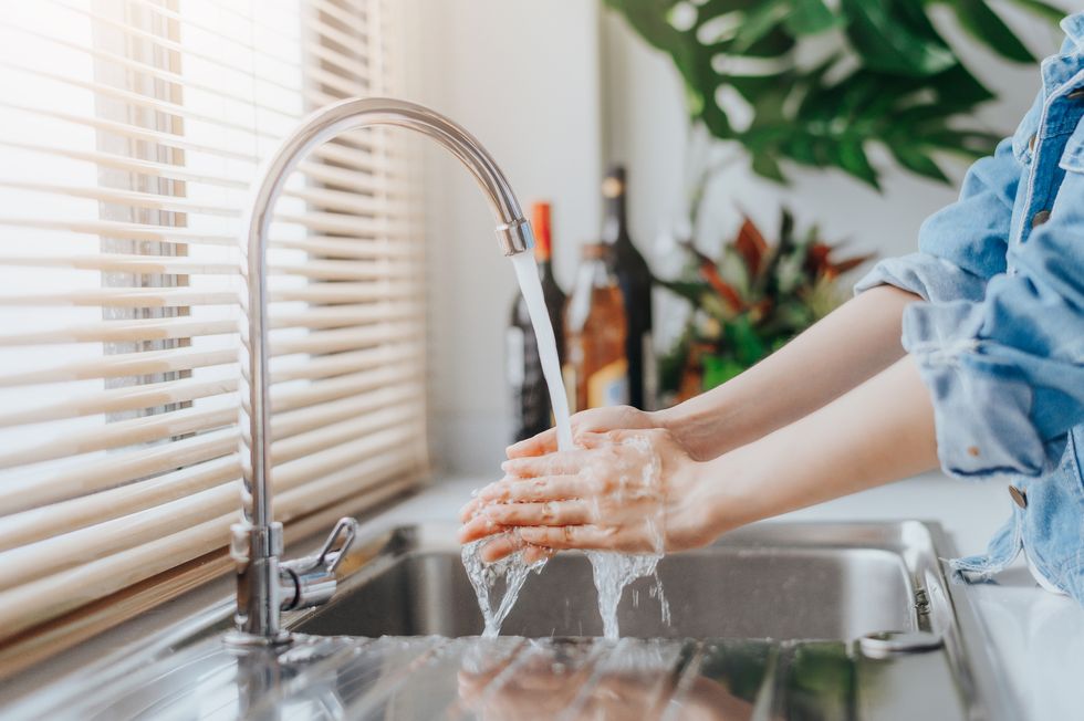 Cropped Image Of Woman Washing Hands At Sink In Kitchen