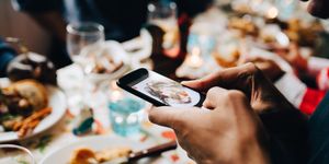 Cropped image of young man photographing food in plate at restaurant