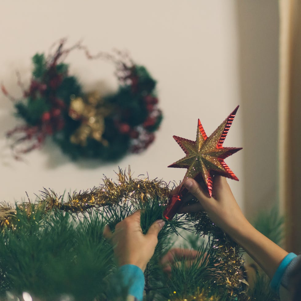 christmas symbols - Cropped Image Person Fixing Tree Topper On Christmas Tree At Home