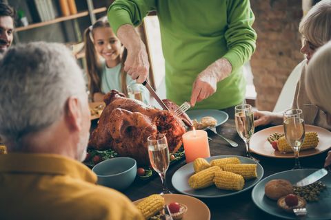 cropped photo of full family sit feast dishes table near roasted turkey grandpa cutting meat into slices hungry relatives waiting excited beginning in living room indoors