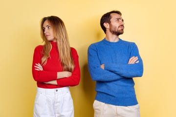 cropped portrait of young couple standing without looking at each other isolated over yellow background