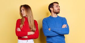 cropped portrait of young couple standing without looking at each other isolated over yellow background