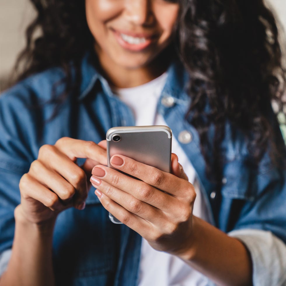 cropped shot of a young woman using smart phone at home