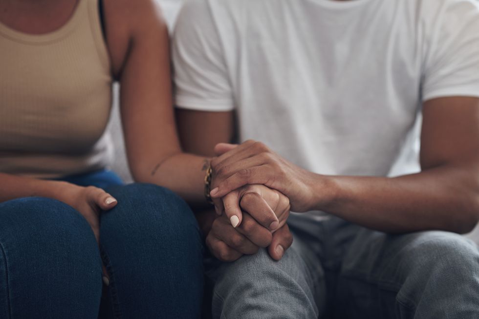 cropped shot of an unrecognizable couple sitting inside together and holding hands