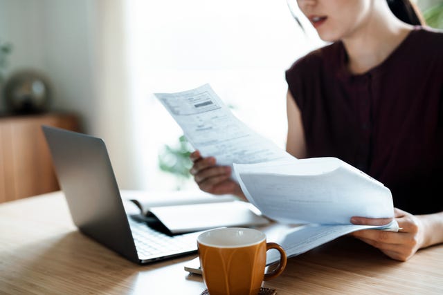 cropped shot of asian woman sitting at dining table, handling personal finance with laptop she is making financial plan and planning budget as she go through her financial bills, tax and expenses at home wealth management, banking and finance concept