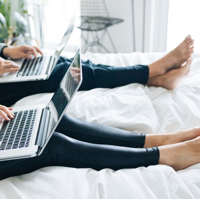 cropped shot of couple using laptops sitting in bed together