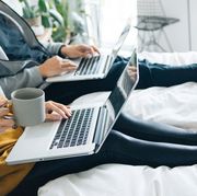 cropped shot of couple using laptops sitting in bed together