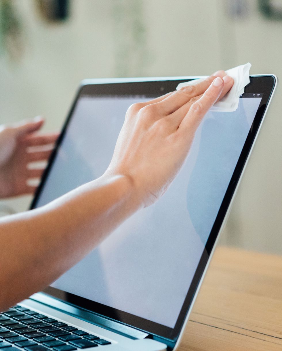 cropped shot of woman cleaning the laptop surface with cleaning wipe
